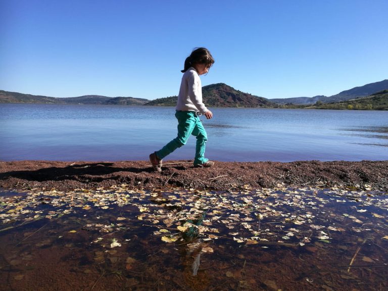Une enfant marche au bord du lac du Salagou